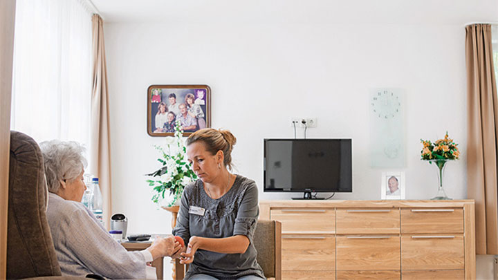 Un membre du personnel prend soin d'un patient dans le centre de soins pour personnes âgées sous l'éclairage dynamique des solutions d'éclairage médical signées Philips