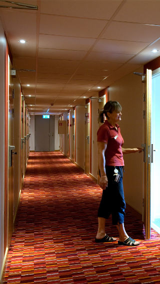 Une femme dans un couloir de l'hôtel Spar, mis en lumière par une solution d'éclairage pour l'hôtellerie de Philips