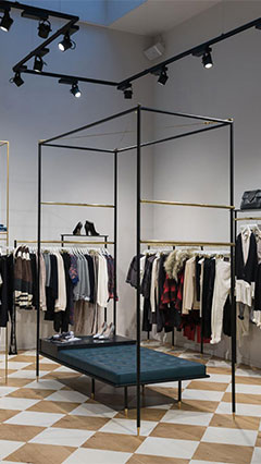 Les produits pendus à des cintres chez SuperTrash, mis en lumière par l'éclairage de commerces Philips