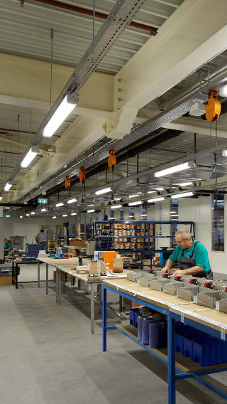 Un employé au travail dans la zone de production du campus Venco, mise en lumière par un système d’éclairage industriel Philips