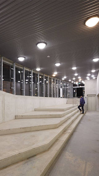  Un homme monte un escalier dans le parking Eiteren, éclairé par un système Philips 