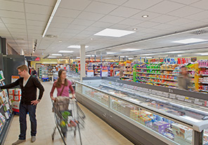 Couple parcourant les rayons d'un supermarché mis en lumière par l'éclairage à économie d'énergie Philips 