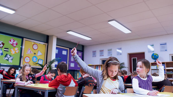 Des enfants concentrés sur une leçon lèvent la main pour répondre à la question du professeur – Un environnement optimal pour l’apprentissage