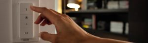 "Interrupteur variateur LED connecté Philips à réglage manuel, contrôlant l'éclairage ambiant dans un salon confortable avec étagères. »